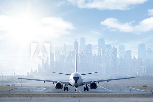 Fototapeta Duży samolot na pasie startowym w dużym mieście