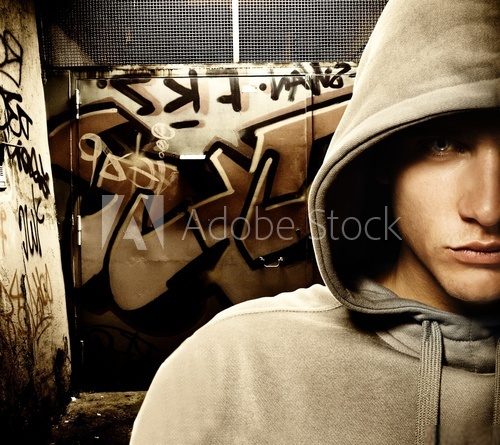 Fototapeta Fajnie wyglądający chuligan w malowanej bramie graffiti