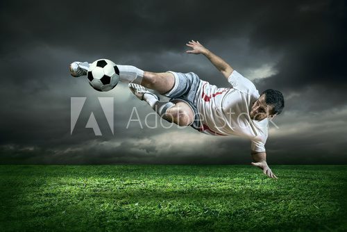 Fototapeta Gracz futbolu z piłką w akci pod deszczem outdoors