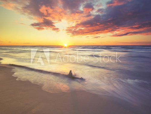 Fototapeta Krajobraz morza o zachodzie słońca, piaszczysta plaża i klif, fale rozbijające się o brzeg stonowane z efektem retro vintage