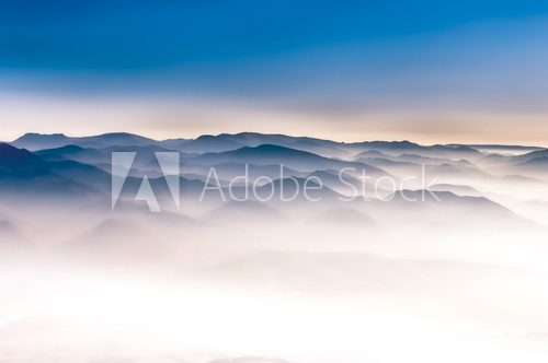 Fototapeta Mglisty góra krajobrazowy widok z niebieskim niebem