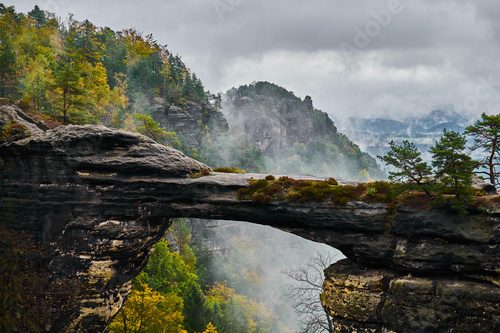 Fototapeta Mglisty krajobraz Bramy Pravcickiej (Pravcicka Brama), największego naturalnego łuku z piaskowca w Europie, w Parku Narodowym Czeskiej Szwajcarii (Ceske Svycarsko)