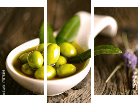 Zielone oliwki w pucharze i gałązka oliwna na drewnianym stole - Obraz trzyczęściowy, Tryptyk